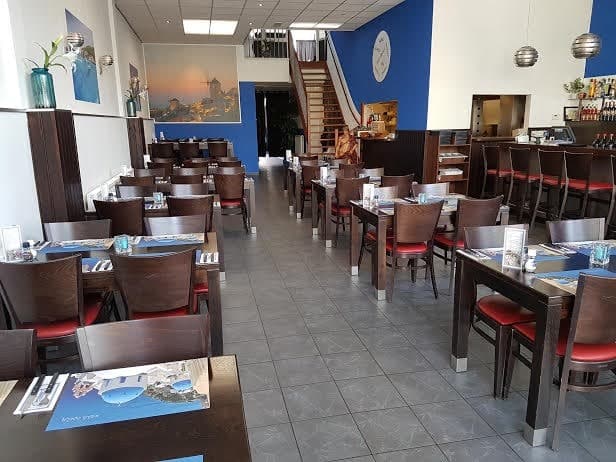 Het restaurant van Nostos met gedekte tafels en Griekse wanddecoratie
