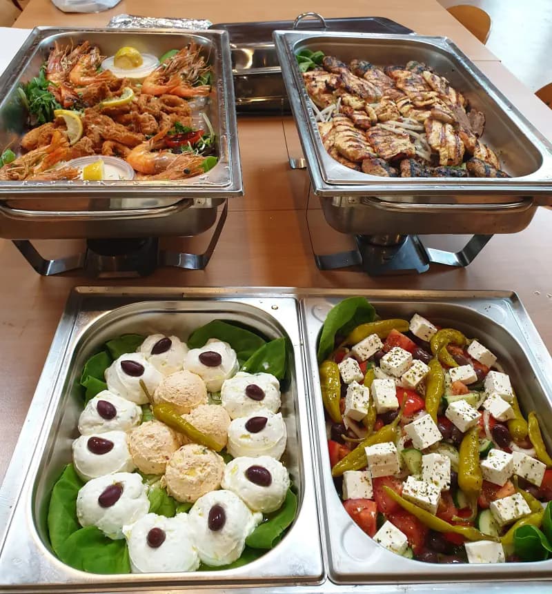Warme en koude cateringschalen met gegrilde kip, scampi's, tzatziki en Griekse salade