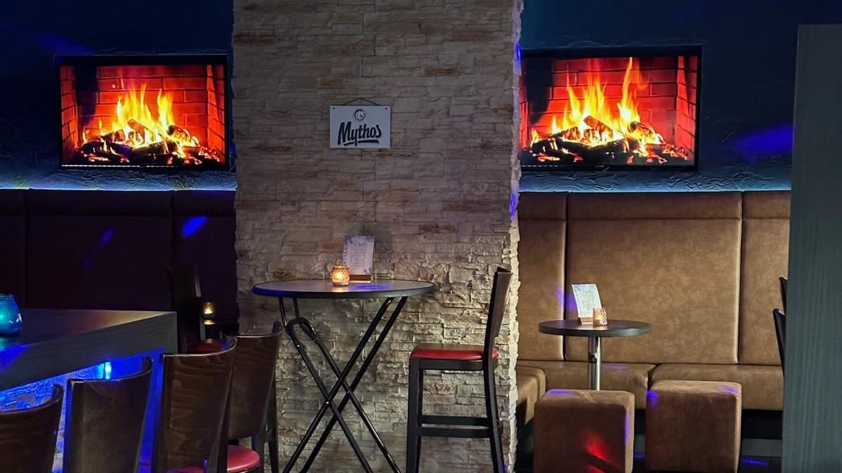 De Mythos Bar naast Restaurant Nostos: sfeerverlichting, open haarden, statafels en lederen banken