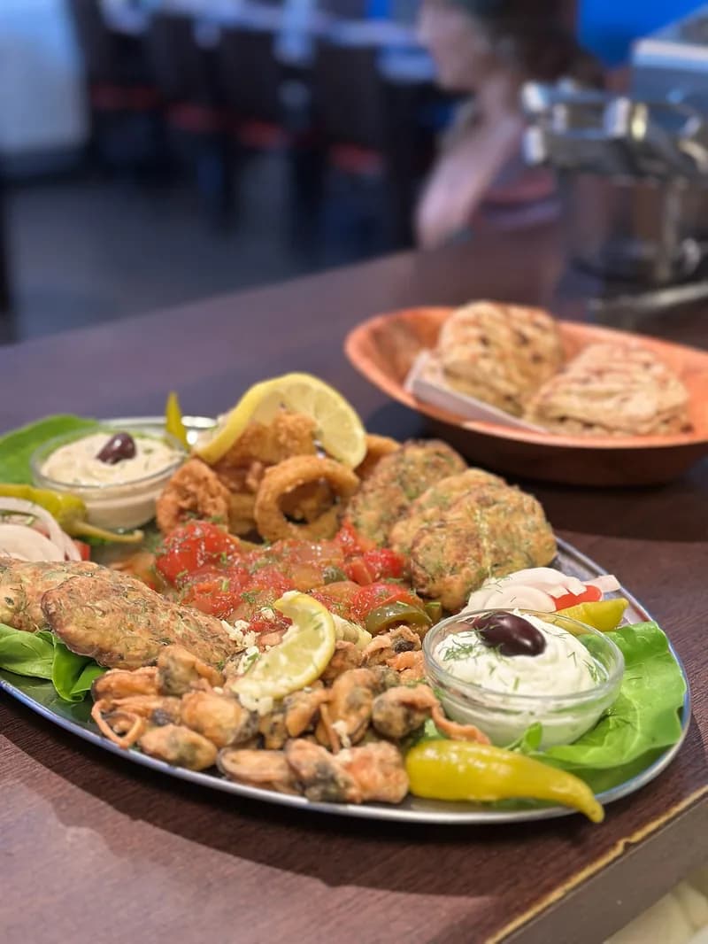 Gemengde schotel met inktvisringen, mosselen, courgettekroketten, tzatziki en pitabrood