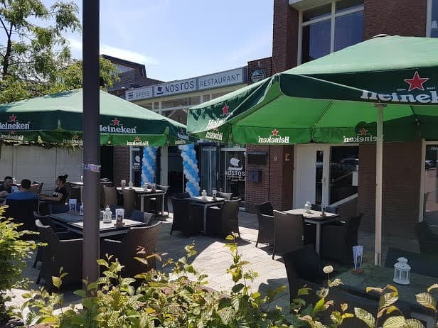 Het terras van Restaurant Nostos met parasols aan de Van Tolstraat in Bodegraven